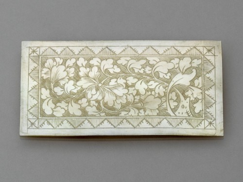 Langwerpig rechthoekig plaatje  van parelmoer met blad- en bloemranken